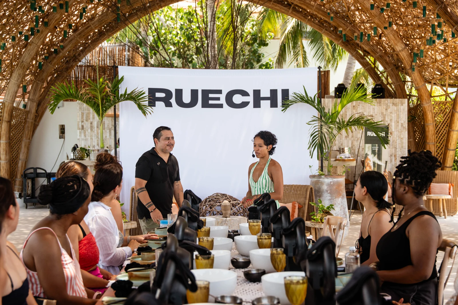 Guests gathered around a shared table beneath woven architecture during a retreat in Isla Mujeres